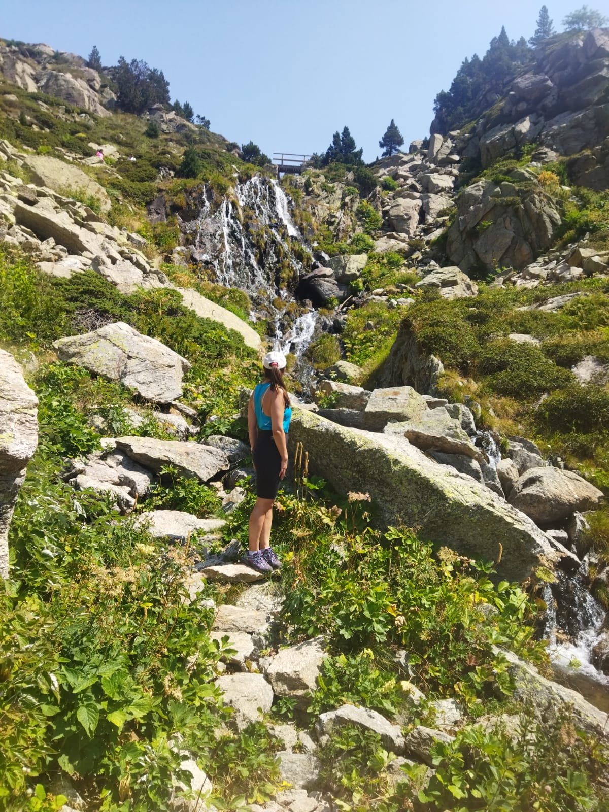 Mujer viajando sola en la montaña junto a una cascada en Andorra